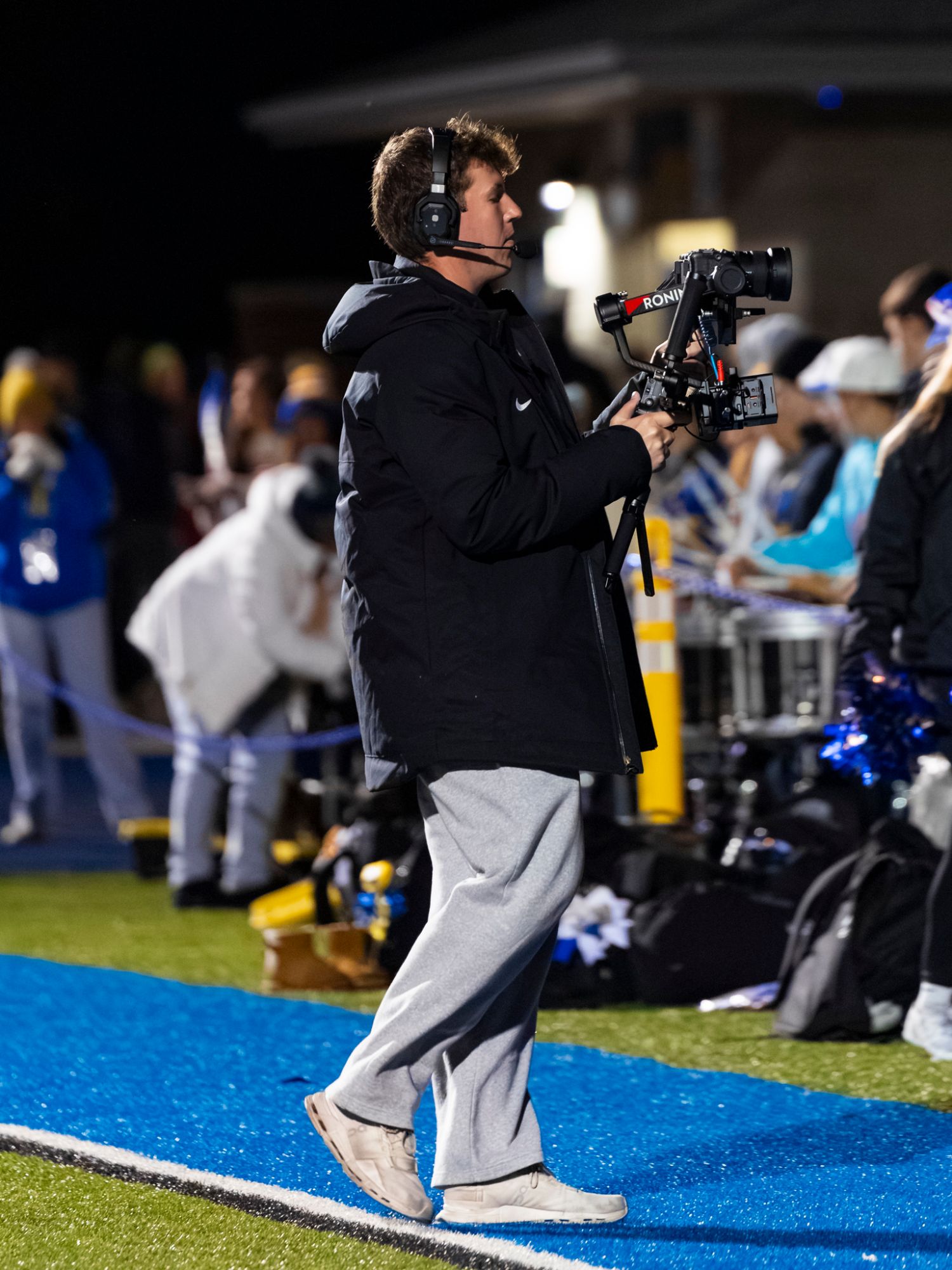 Ethan Jaworski filming on the sideline with a gimbal at a night game