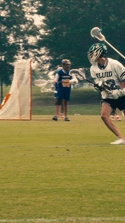 A Fluid Lacrosse player running with the ball at a summer tournament